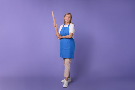 Woman with rolling pin on violet backgroundの写真素材
