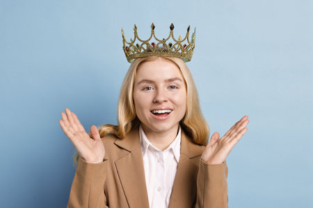 Happy businesswoman in elegant crown on light blue backgroundの写真素材
