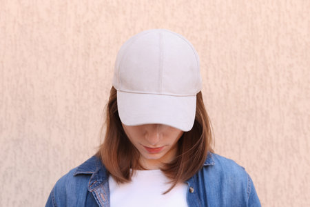 Woman in stylish baseball cap near beige wall. Mockup for designの写真素材