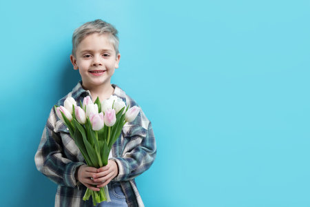 Cute little boy with bouquet of tulips on light blue background. Space for textの写真素材