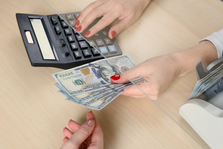 Cashier giving dollar banknotes to client at table in money exchange, closeupの写真素材