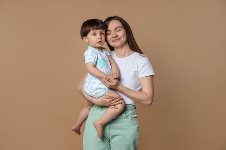 Family portrait of mother with her little son on beige backgroundの写真素材