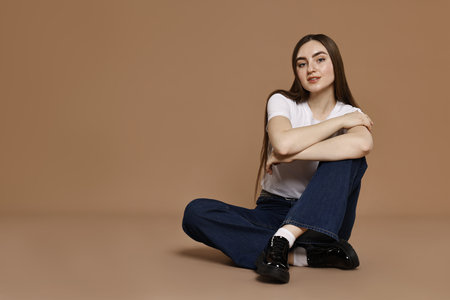 Woman in stylish jeans on brown background.の写真素材