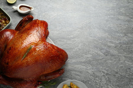 Whole baked turkey and other dishes served on grey table, flat lay. Space for text