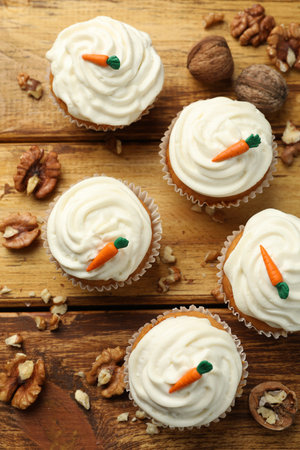 Delicious carrot cupcakes and walnuts on wooden table, flat layの写真素材