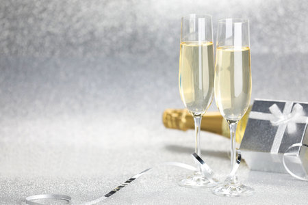 Champagne in glasses, bottle, gift box and streamers on silver background. Space for textの写真素材