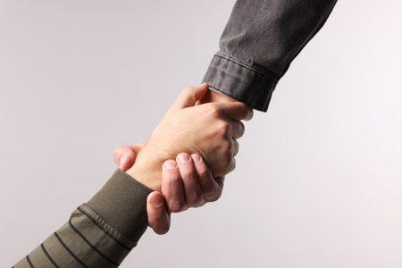 Help and support. People holding hands on light gray background, closeupの写真素材