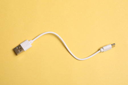 One USB charge cable on yellow background, top viewの写真素材