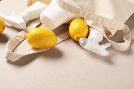 Shopping bag with bottles of different cleaning products and lemons on beige background, closeupの写真素材