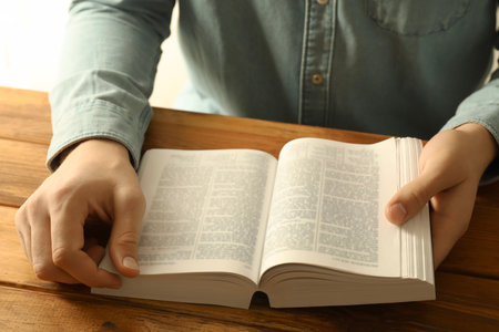 Man reading Holy Bible in English language at wooden table, closeupの写真素材