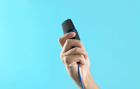 Man with microphone on light blue background, closeup