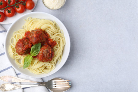 Delicious pasta with meatballs in bowl served on light table, flat lay. Space for textの写真素材