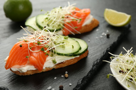 Delicious bruschette with salmon, cream cheese and cucumber on grey table, closeupの写真素材