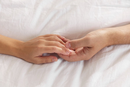 Lovely couple holding hands in bed, top viewの写真素材