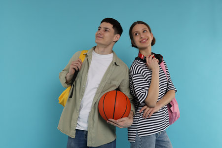 Students with backpacks and basketball ball on light blue backgroundの写真素材
