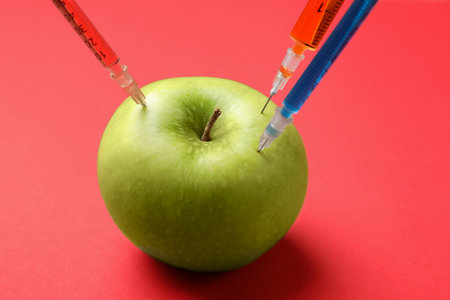 Green apple with different syringes on red background, closeupの写真素材