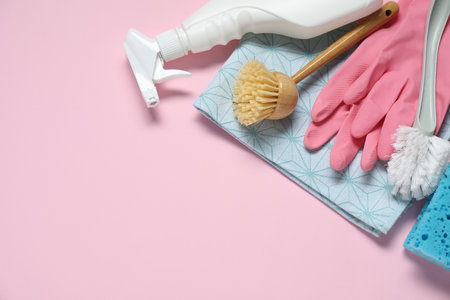 Detergent and supplies on pink background, flat lay. Space for text