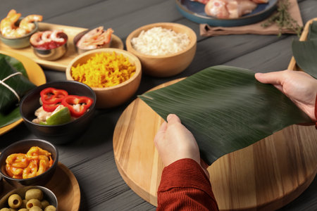 Woman with banana leaf at wooden table with different products, closeup. Healthy eco servingの写真素材