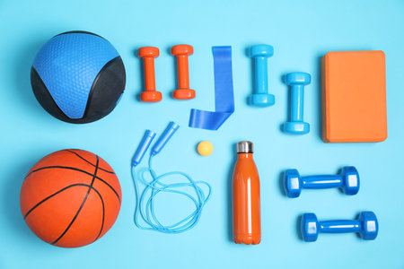 Different sports equipment and water bottle on light blue background, flat layの写真素材