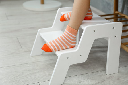 Little girl standing on step stool indoors, closeup