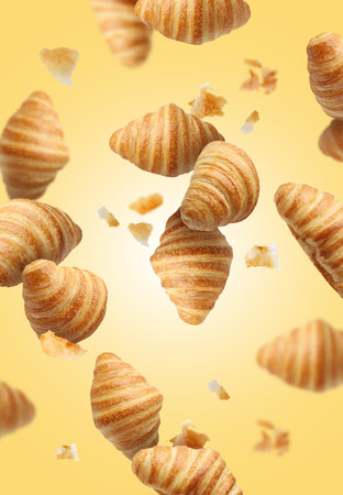 Delicious croissants and crumbs in air on golden background. Puff pastryの写真素材