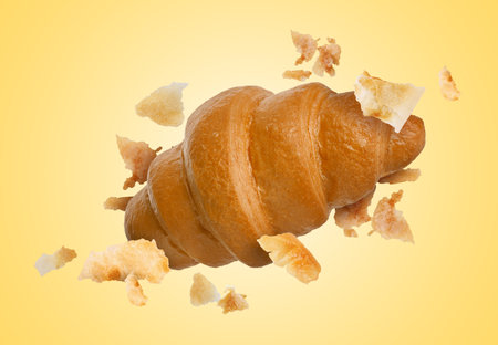 Delicious croissant and crumbs in air on golden background. Puff pastryの写真素材