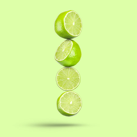 Fresh lime slices falling on light green backgroundの写真素材