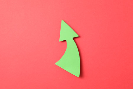 One green paper arrow on red background, top viewの写真素材