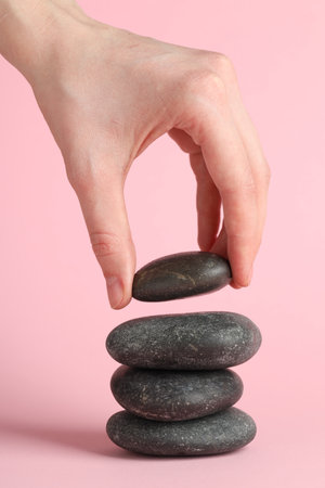 Woman making stack of stones on pink background, closeup. Harmony and life balanceの写真素材