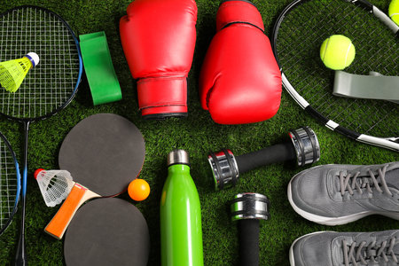 Different sport equipment on artificial grass, flat lay