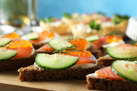 Tasty canapes with salmon and cucumber on wooden board, closeupの写真素材