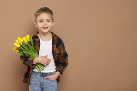 Cute little boy with bouquet of tulips on brown background. Space for text