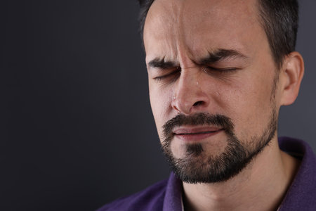 Man crying on grey background, closeup. Space for textの写真素材