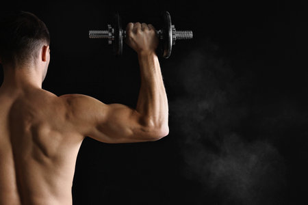 Man training with barbell on black background, back view.の写真素材