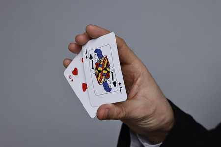 Illusionist with playing cards on grey background, closeup