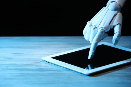 Artificial intelligence. Robot hand using tablet at wooden table, closeup. Space for text