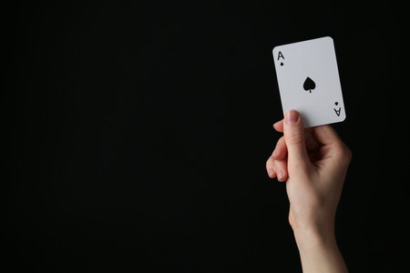 Woman with playing card against black background, closeup. Space for text