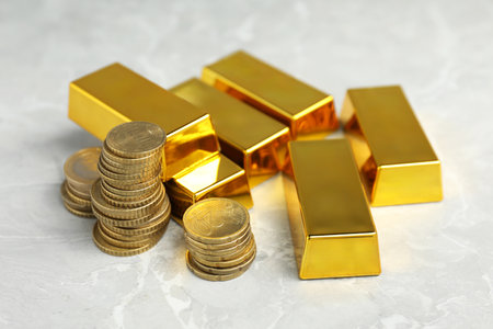 Gold bars and coins on gray marble table, closeupの写真素材