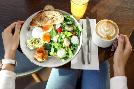 Woman having tasty breakfast in cafe, top viewの写真素材