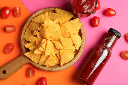 Tasty ketchup, tomatoes and nachos on color background, flat layの写真素材