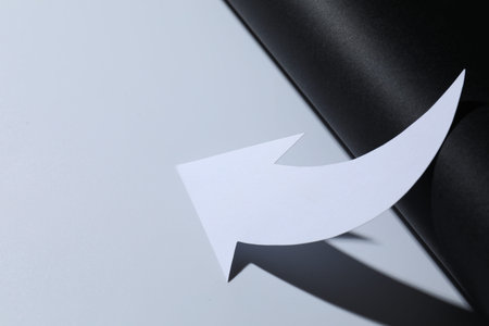 One white paper arrow on color background, closeup