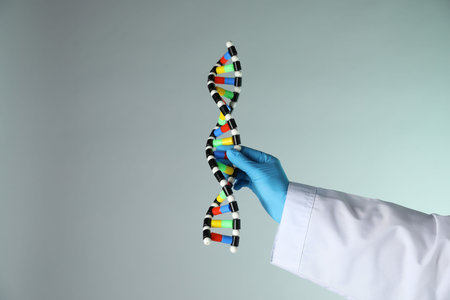 Scientist with DNA structure model on color background, closeup