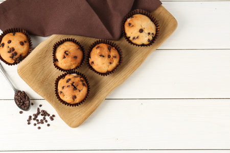Delicious muffin with chocolate chips on white wooden table, flat lay. Space for textの写真素材