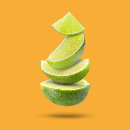 Fresh lime slices falling on orange backgroundの写真素材