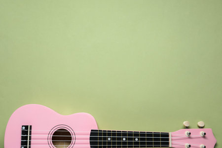 One ukulele on light olive background, top view. Space for text