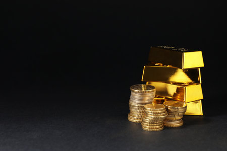 Gold bars and coins on black table, space for textの写真素材