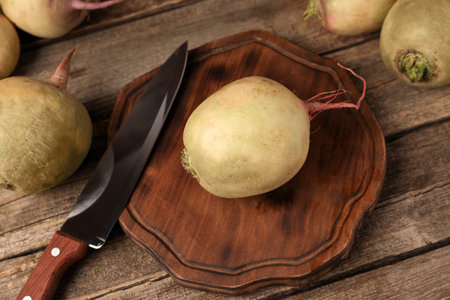 Fresh turnips and knife on wooden table, closeup