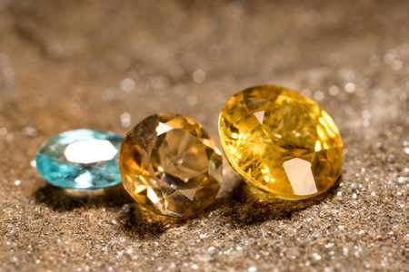 Beautiful shiny gemstones on sand, closeup viewの写真素材