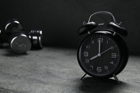 Alarm clock and dumbbells on gray backgroundの写真素材