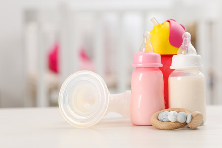 Feeding bottles with milk, breast pump and teether on white table indoorsの写真素材